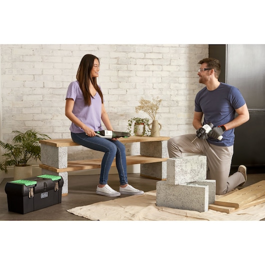 Photo of BLACK+DECKER BDST60120 black toolbox with green latches on floor next to two people working on a DIY project.