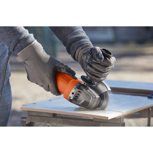 BLACKDECKER BEG110 angle grinder photography showing orange and black tool cutting tile outdoors.