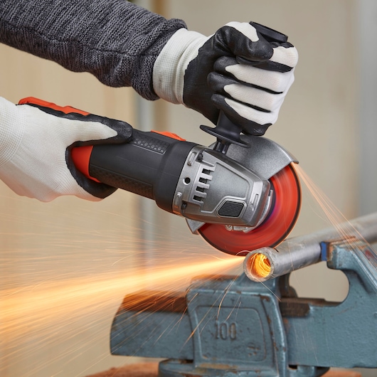 BLACKDECKER BEG220KA5 angle grinder cutting metal pipe, close-up action photography.