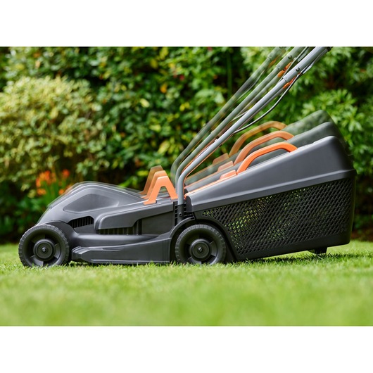 BLACKDECKER BEMW351 lawn mower with adjustable handle on grass, side profile, garden background.