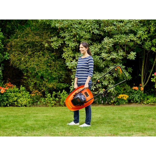 BLACK+DECKER BEMWH551 orange hover lawn mower held upright by person in garden.