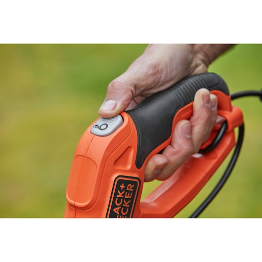 Close-up photo of BLACK+DECKER BESTE630CM orange and black handle with power button held in a hand.