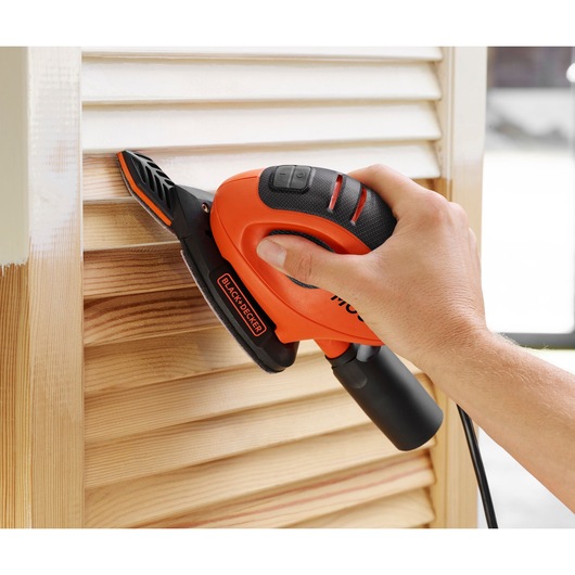 Photo of BLACKDECKER BEW230BC detail sander used on wooden shutters, showing ergonomic design and compact size.