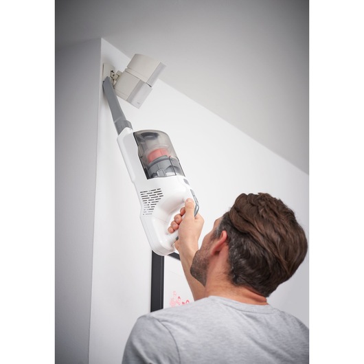BLACKDECKER BHFEA515J vacuum cleaner used for cleaning a high corner, photography shows handheld operation.