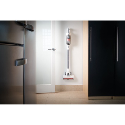 Photo of BLACKDECKER BHFEA515J cordless stick vacuum cleaner mounted on a white kitchen wall.