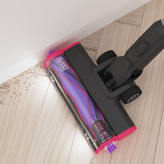 Photo of BLACK+DECKER BHFEA640WP cordless vacuum cleaner head with pink and purple accents cleaning debris near a wall.