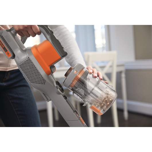 Photo of BLACK+DECKER BHFEV182B cordless vacuum cleaner, close-up showing dust container being emptied indoors.