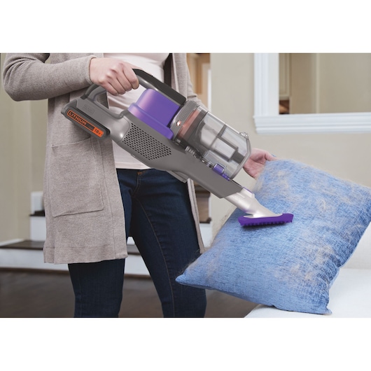 Photo of BLACK+DECKER BHFEV182CP cordless vacuum cleaner with purple accents cleaning pet hair from a blue pillow.
