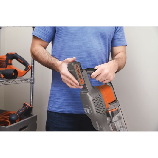 Photo of BLACK+DECKER BHFEV182C cordless vacuum cleaner with removable battery held by a person indoors.