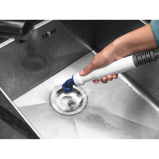 BLACK+DECKER BHSM1615DSG steam cleaner scrubbing metal sink, close-up of hand holding white and blue cleaning tool.