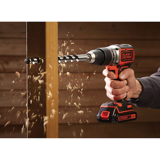 BLACKDECKER BL188KB cordless drill being used to drill through wood with wood shavings flying.