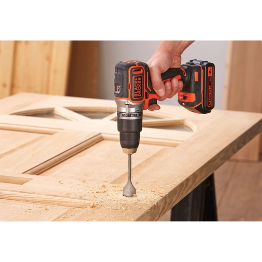 BLACKDECKER BL188KB cordless drill in use on wooden door, close-up of hand and tool.
