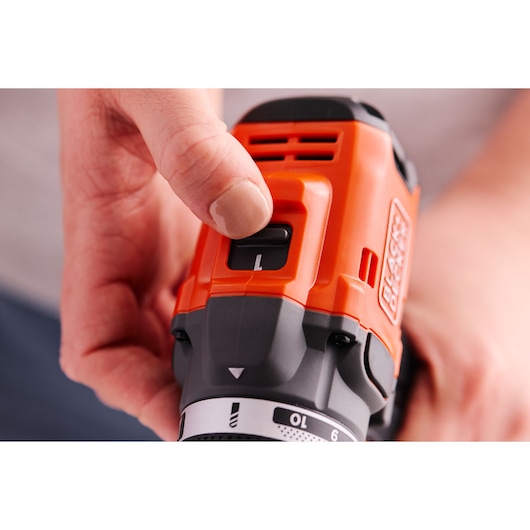 Photo of BLACKDECKER BLD682XN drill close-up, hand adjusting top switch, orange and black design.