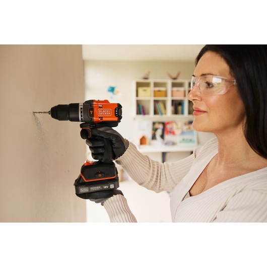 Photo of BLACKDECKER cordless drill BLD683D1 in use, drilling into indoor wall, person wearing work gloves.