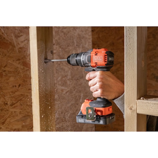Photo of BLACK+DECKER BLD782E1K cordless drill in use, drilling into wood frame in construction setting.