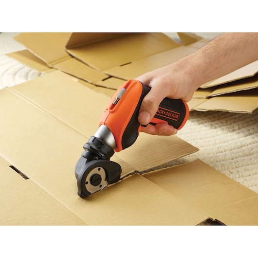 BLACKDECKER CSCA3 cordless rotary cutter used to cut cardboard, close-up photo of tool in action.