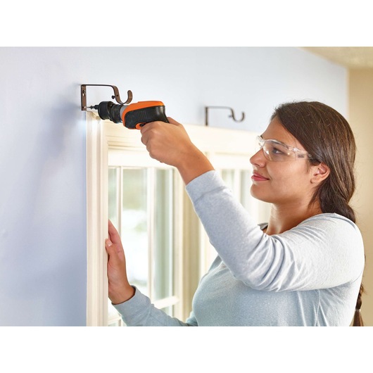Photo of BLACKDECKER CSOA2 cordless screwdriver in use mounting a curtain bracket on a wall.