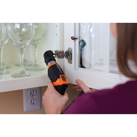BLACKDECKER CSRA1 cordless screwdriver in use on cabinet hinge, close-up indoor photography.
