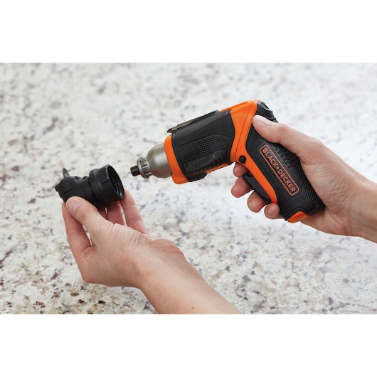 BLACK+DECKER CSRA1 cordless screwdriver with black and orange handle, held in hand with removable bit attachment.