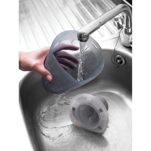 BLACKDECKER DV1210N vacuum dust container being rinsed under a faucet in a kitchen sink.