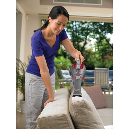 BLACKDECKER DV1415EL handheld vacuum cleaning couch in living room, person holding device.