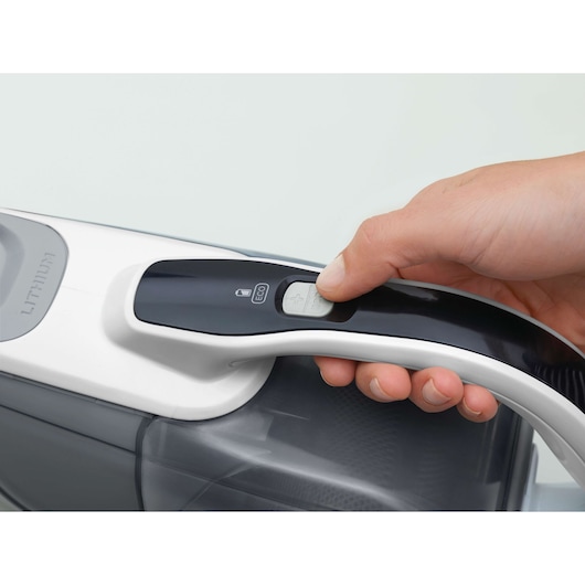 BLACKDECKER DVJ215J handheld vacuum cleaner close-up, hand pressing power button, white and black design.
