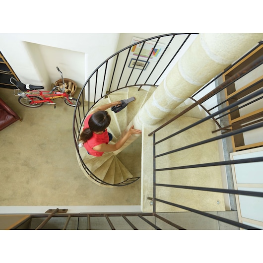 BLACKDECKER DVJ325BFS handheld vacuum in use on spiral staircase, indoor setting, photography