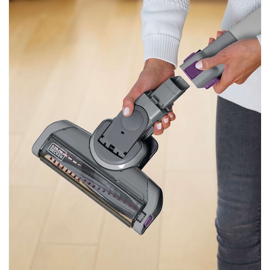 BLACKDECKER FEJ520JFS vacuum cleaner head in grey with purple accents held by a person indoors.