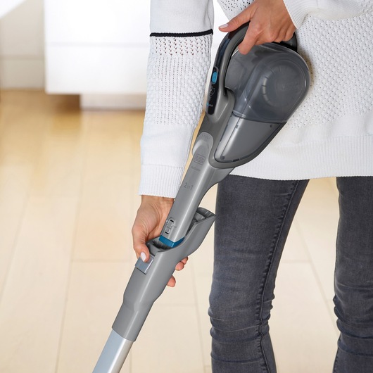 Photo of BLACKDECKER FEJ520JF cordless handheld vacuum cleaner in use, gray color, close-up on handle and extension.