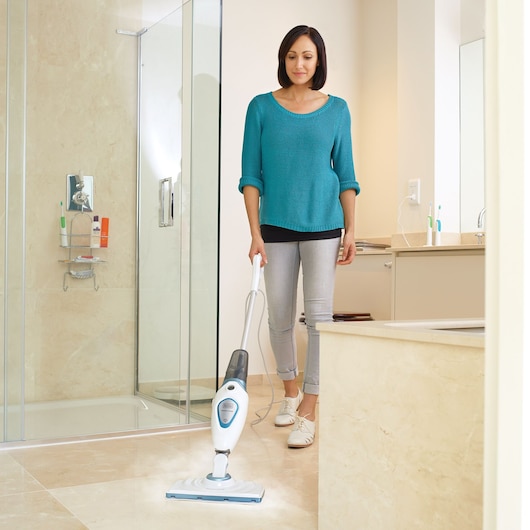 BLACKDECKER FSM1605 steam mop cleaning tile floor in a bathroom, front angle view.