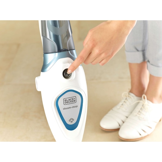 Photo of BLACK+DECKER FSM1605 steam mop being turned on, close-up view of button pressed by hand.