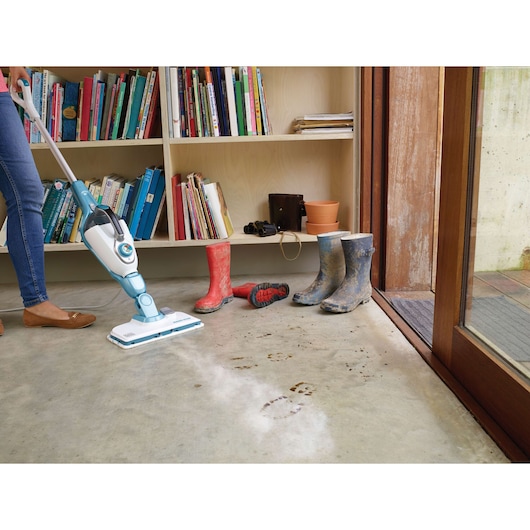 BLACKDECKER FSMH13101SM steam mop cleaning muddy footprints near boots, indoor setting, side angle