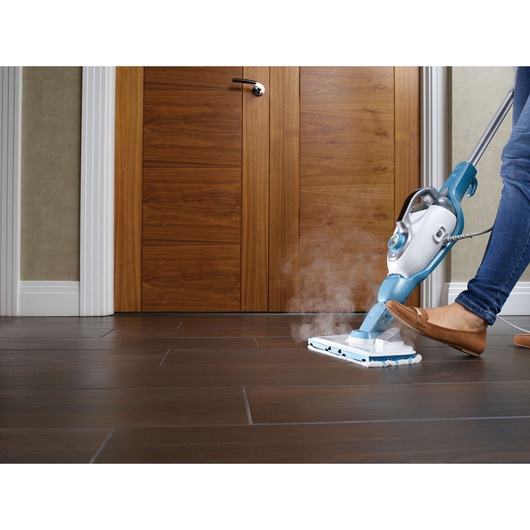 BLACKDECKER FSMH13101SM steam mop cleaning dark wooden floor near closed door, side angle.