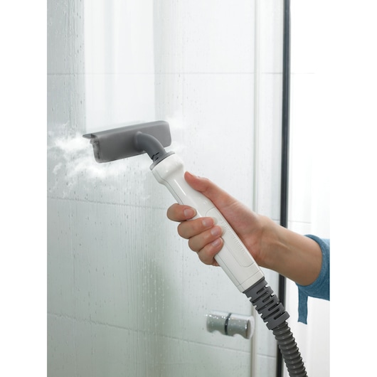BLACKDECKER FSMH13151SM steam cleaner cleaning glass shower door with gray and white handheld attachment.