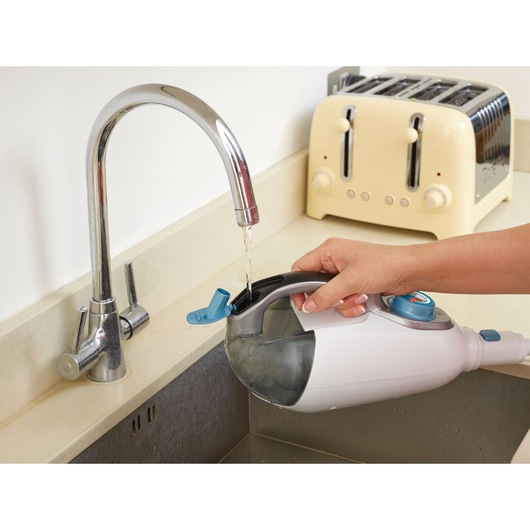 BLACKDECKER FSMH13151SM steam cleaner tank being filled with water at kitchen sink, angled side view.