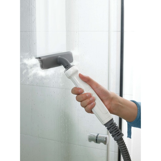 BLACKDECKER FSMH1321 steam cleaner handheld cleaning tile wall with grey attachment, side angle.