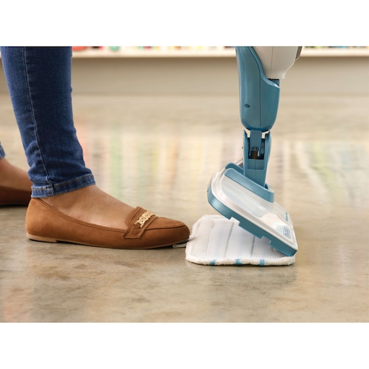 BLACKDECKER FSMH1321 steam mop head and pad close-up, blue and white, next to a person’s brown shoe.