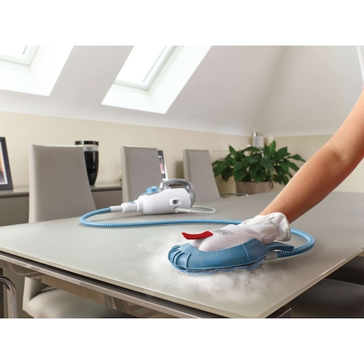 BLACKDECKER FSMH1351SM steam cleaning glove and unit used on a tabletop in a modern dining room.