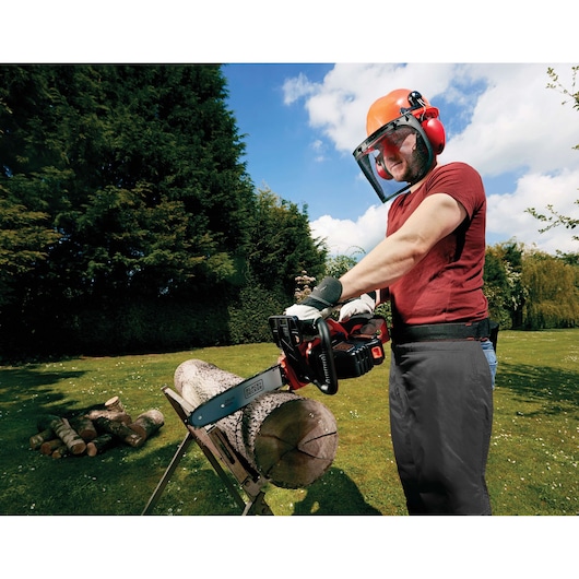 Photo of BLACK+DECKER GKC1825L20 cordless chainsaw in use, cutting a log outdoors on a sawbuck.