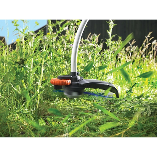 BLACKDECKER GL7033 grass trimmer cutting tall weeds in outdoor garden, close-up photography.