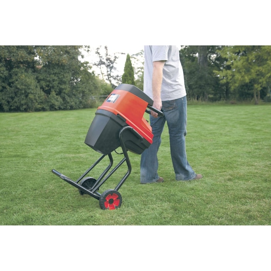 BLACKDECKER GS2400 garden shredder with red and black casing, wheeled, being moved on grass.