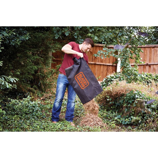 BLACKDECKER GW2500 garden vacuum bag used to empty mulch onto a leafy yard, outdoor setting.