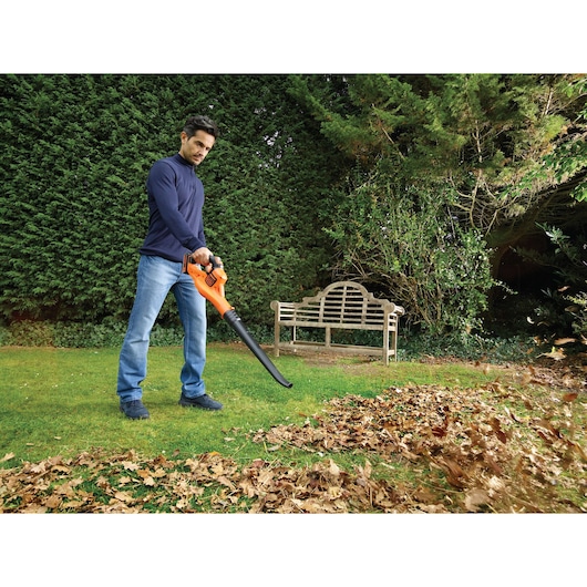 BLACKDECKER GWC1820PC leaf blower in use outdoors moving leaves on grass near bench.