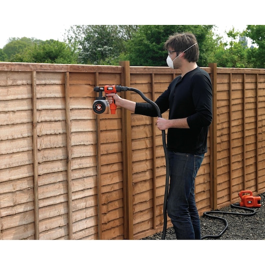 BLACKDECKER HVLP400 paint sprayer used on wooden fence outdoors, product in action photography.