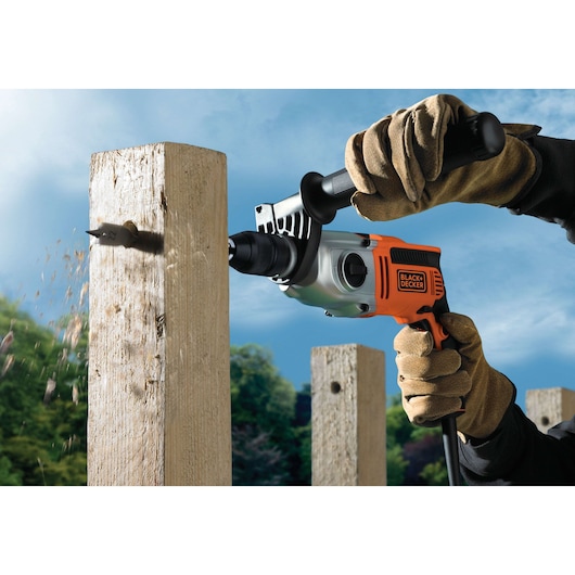 BLACKDECKER KR7532K electric drill in use, drilling through a wooden post outdoors.
