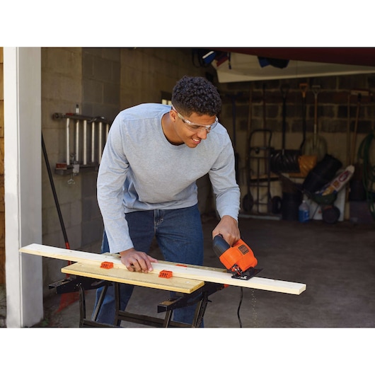 Photo of BLACKDECKER KS701E jigsaw cutting wood plank in workshop setting.