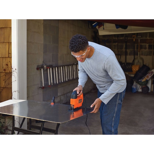 BLACKDECKER KS701E jigsaw cutting metal sheet in a garage workshop.