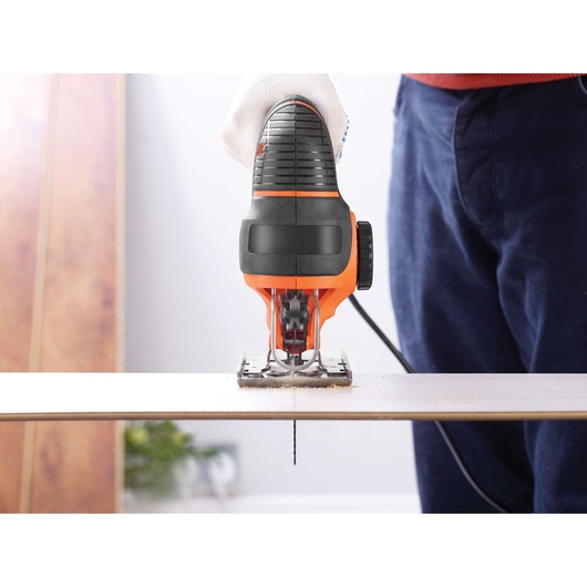 BLACKDECKER KS901PEK jigsaw cutting wood, front view, handheld in workshop setting.