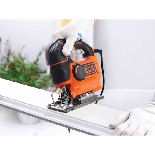 BLACKDECKER jigsaw KS901PEK in use, orange and black design, cutting wood, close-up view.