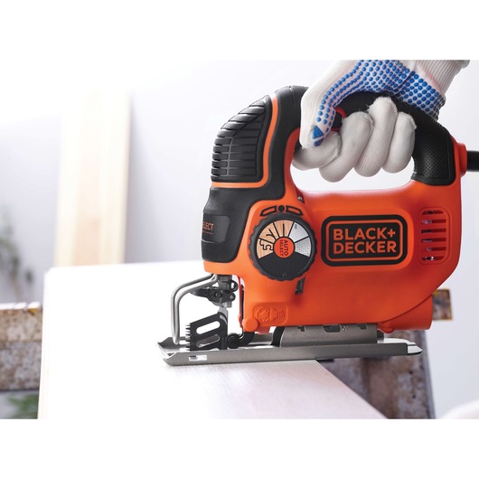 BLACK+DECKER KS901SEK jigsaw in use, orange and black, close-up side view on wood.